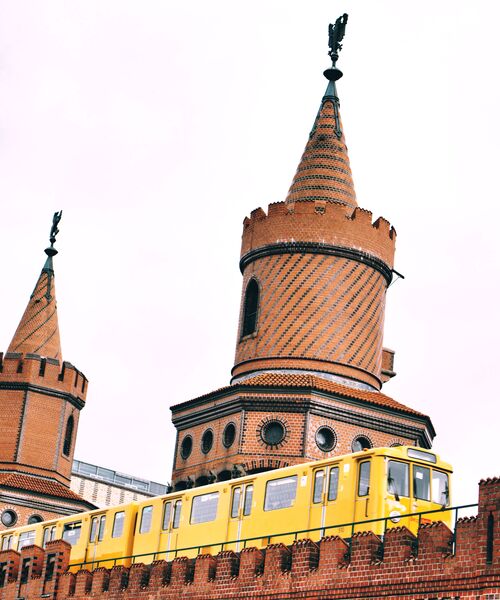 Gelbe U-Bahn fährt über die Oberbaumbrücke mit ihren markanten Backsteintürmen in Berlin.