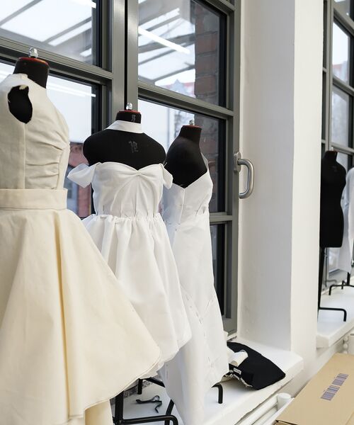 Schneiderpuppen mit weißen Kleid-Entwürfen in einem hellen Atelierraum.